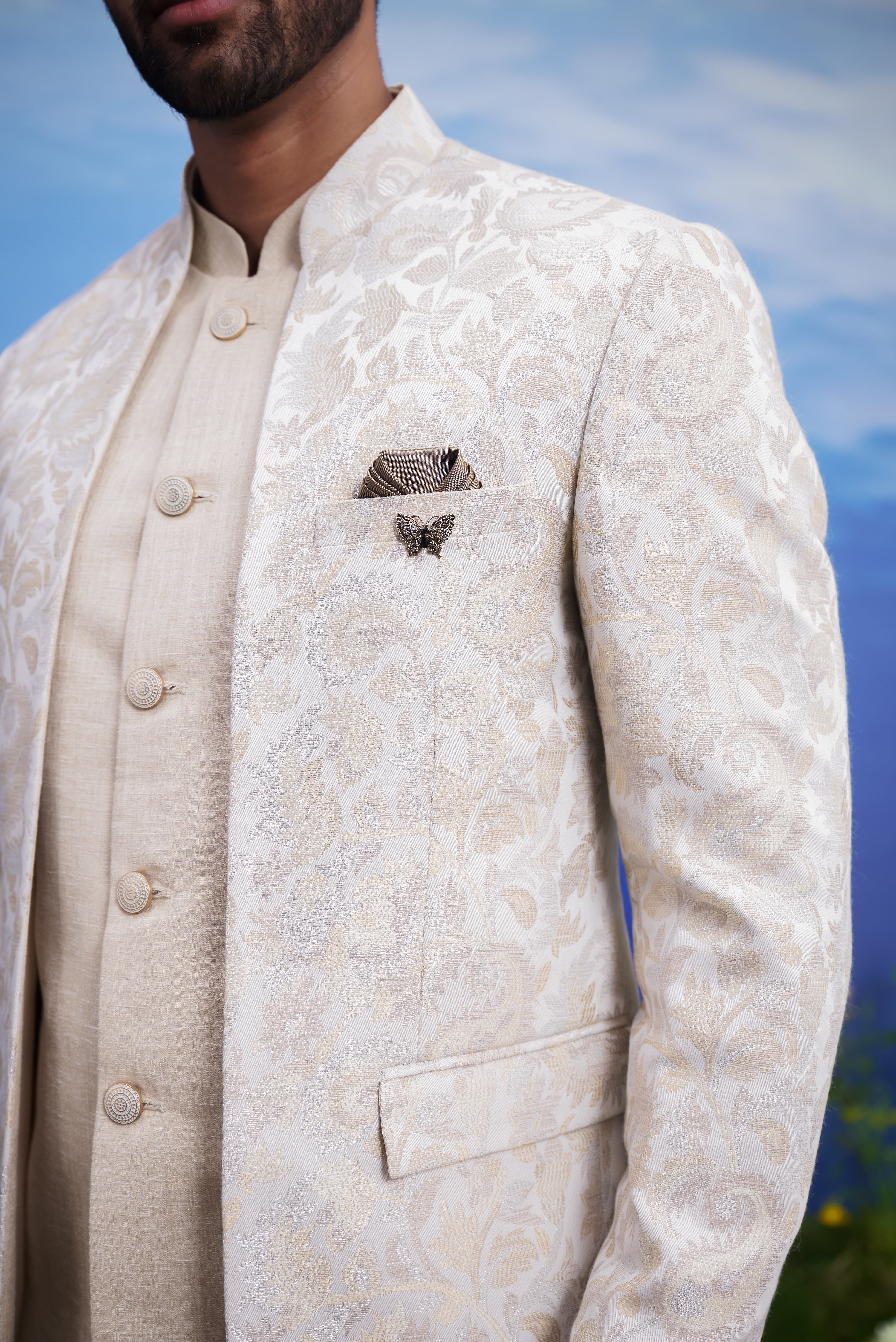 Beige jacquard Bandhgala suit, men's ethnic formal wear, featuring a jacquard Bandhgala, linen sleeveless jacket, trousers, pocket square, and pin.