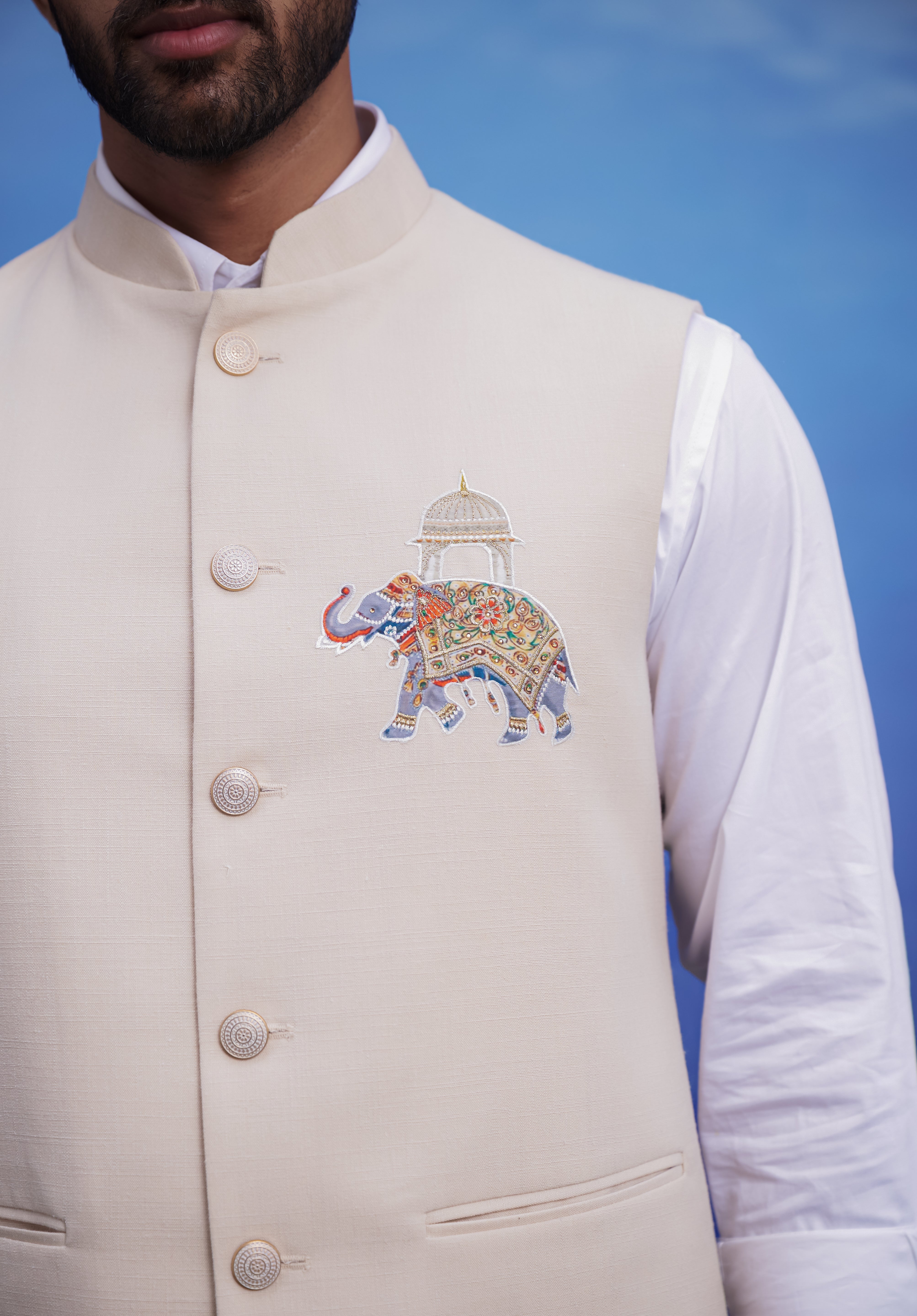 Close-up of the beige Nehru jacket, highlighting the embroidered motif and linen blend fabric.