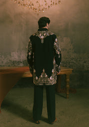 A man viewed from behind wearing a black embroidered short kurta with intricate embroidery.