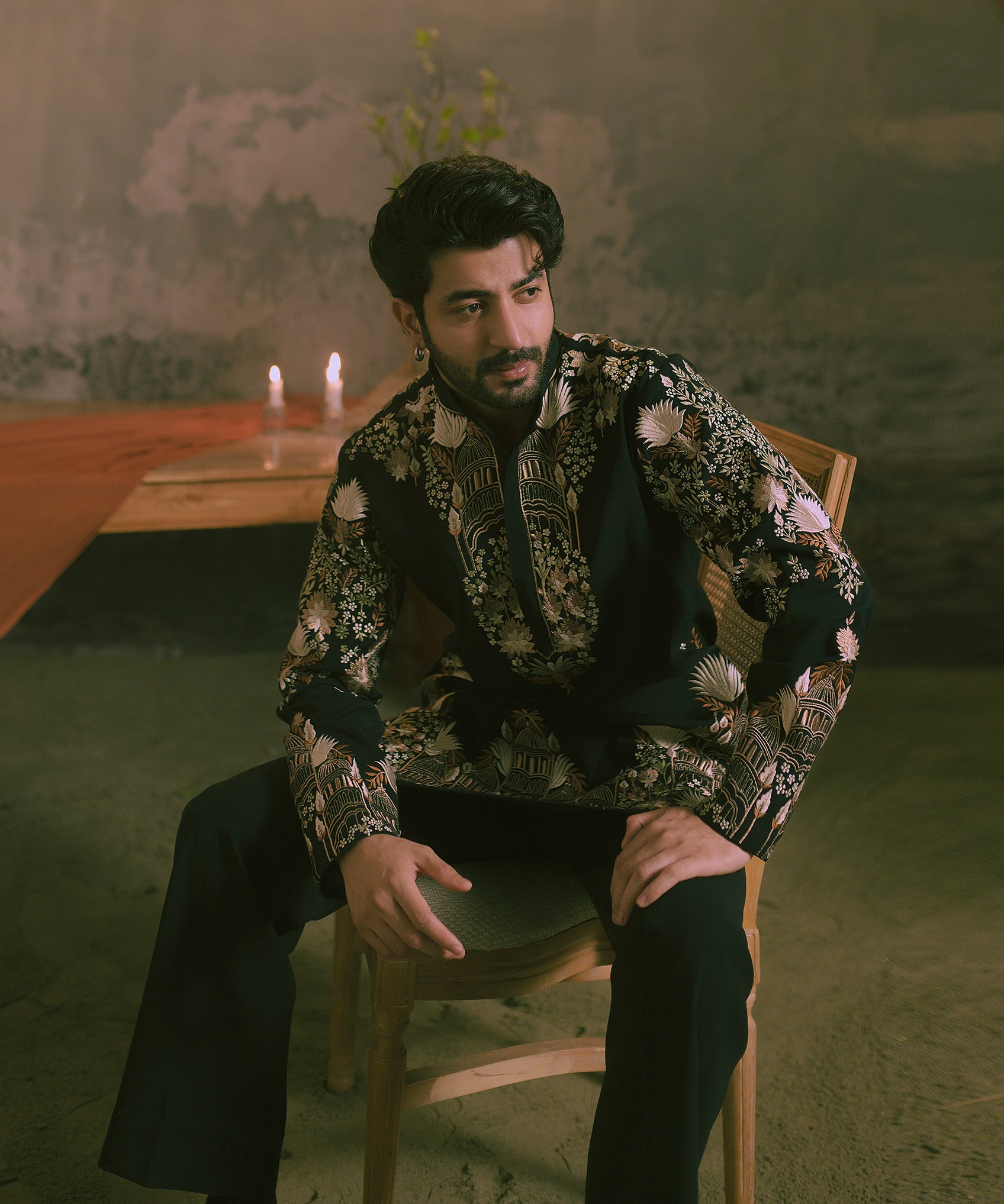 A man wearing a black embroidered kurta with black trousers.