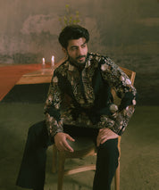A man wearing a black embroidered kurta with black trousers.