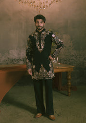 A man wearing a black heavily embroidered traditional kurta with matching trousers.