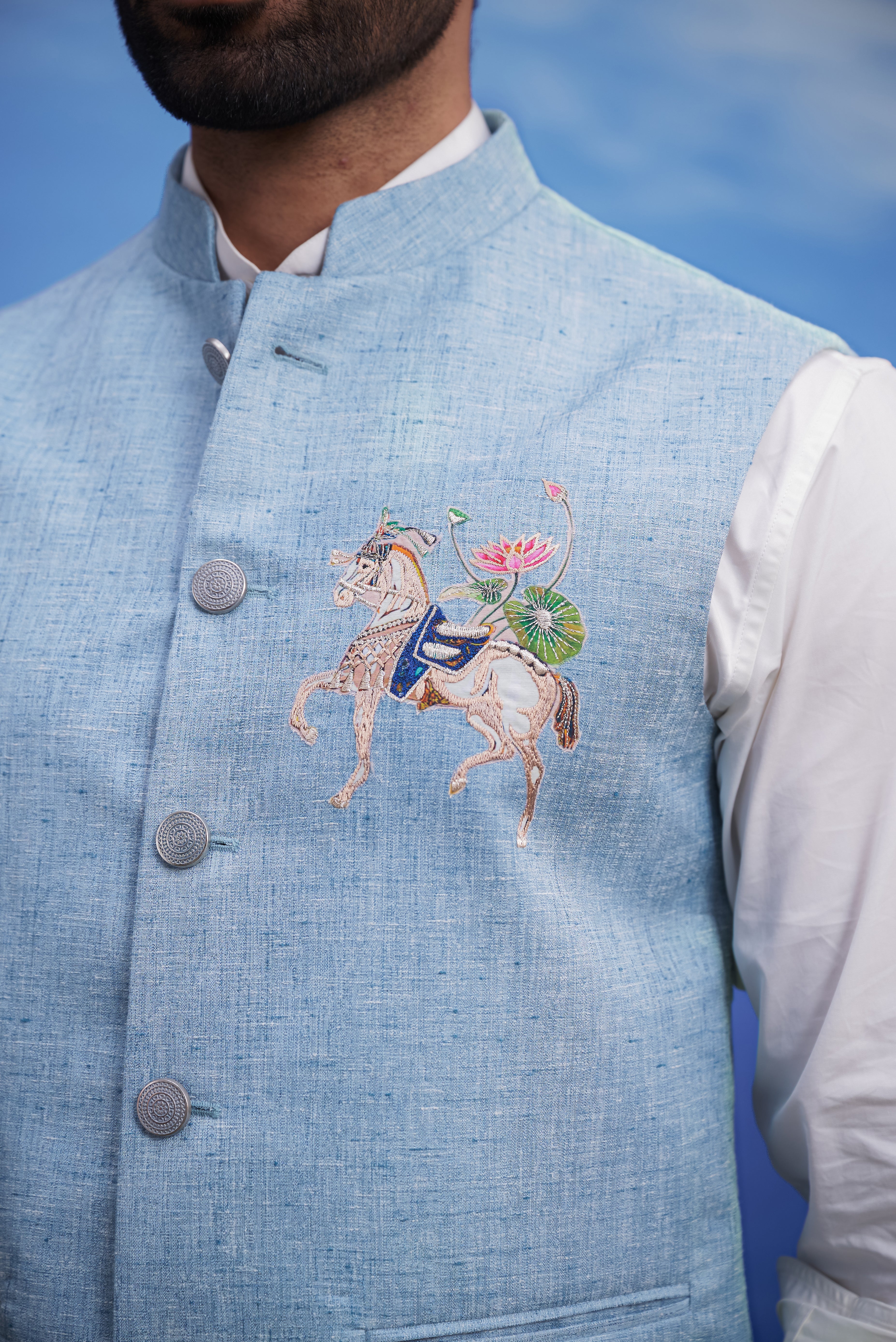 Close-up of the blue Nehru jacket, highlighting the embroidered motif and linen blend fabric.