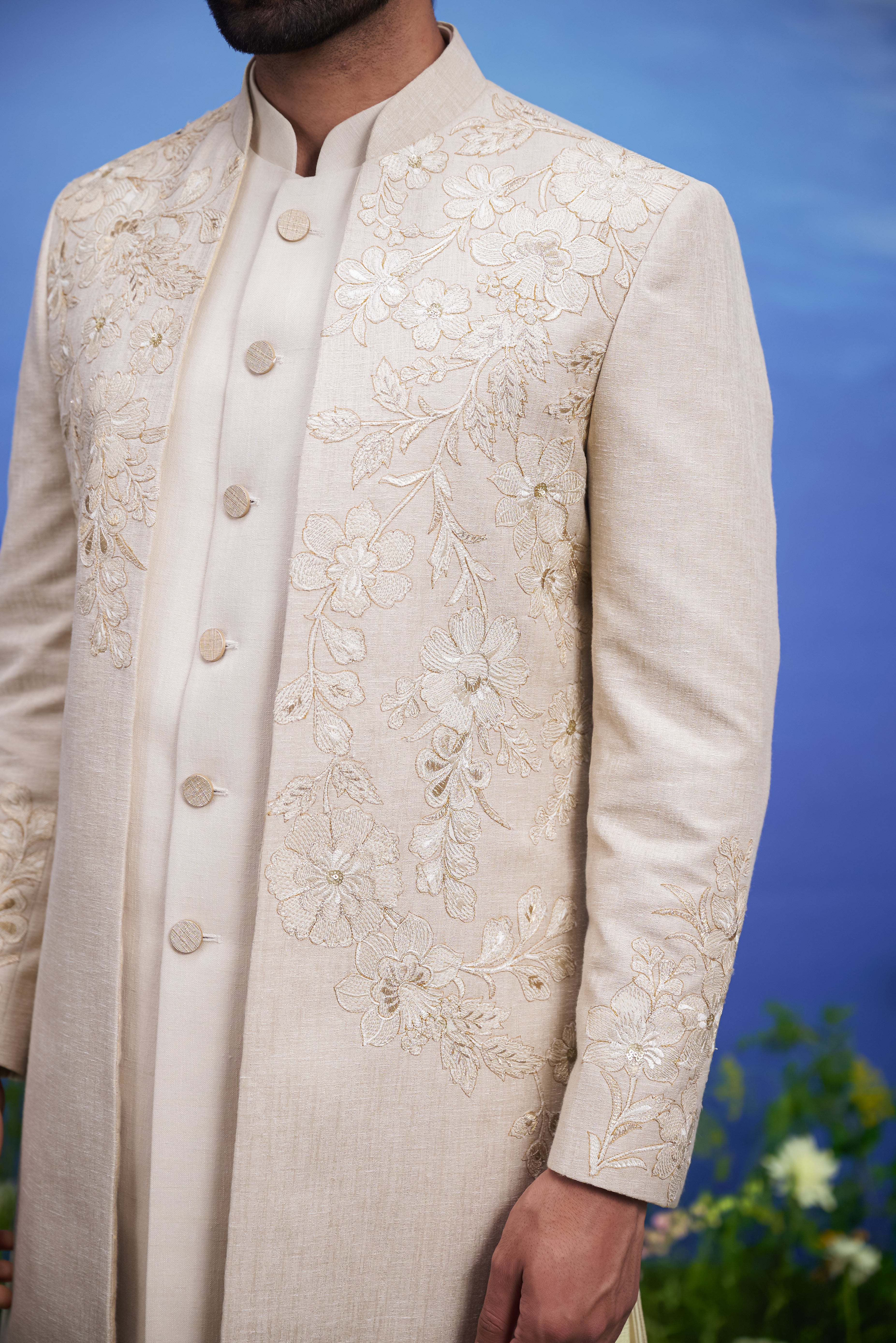 Men's cream Indo-western suit with floral embroidery and zari detailing, displayed on a product page with size options.
