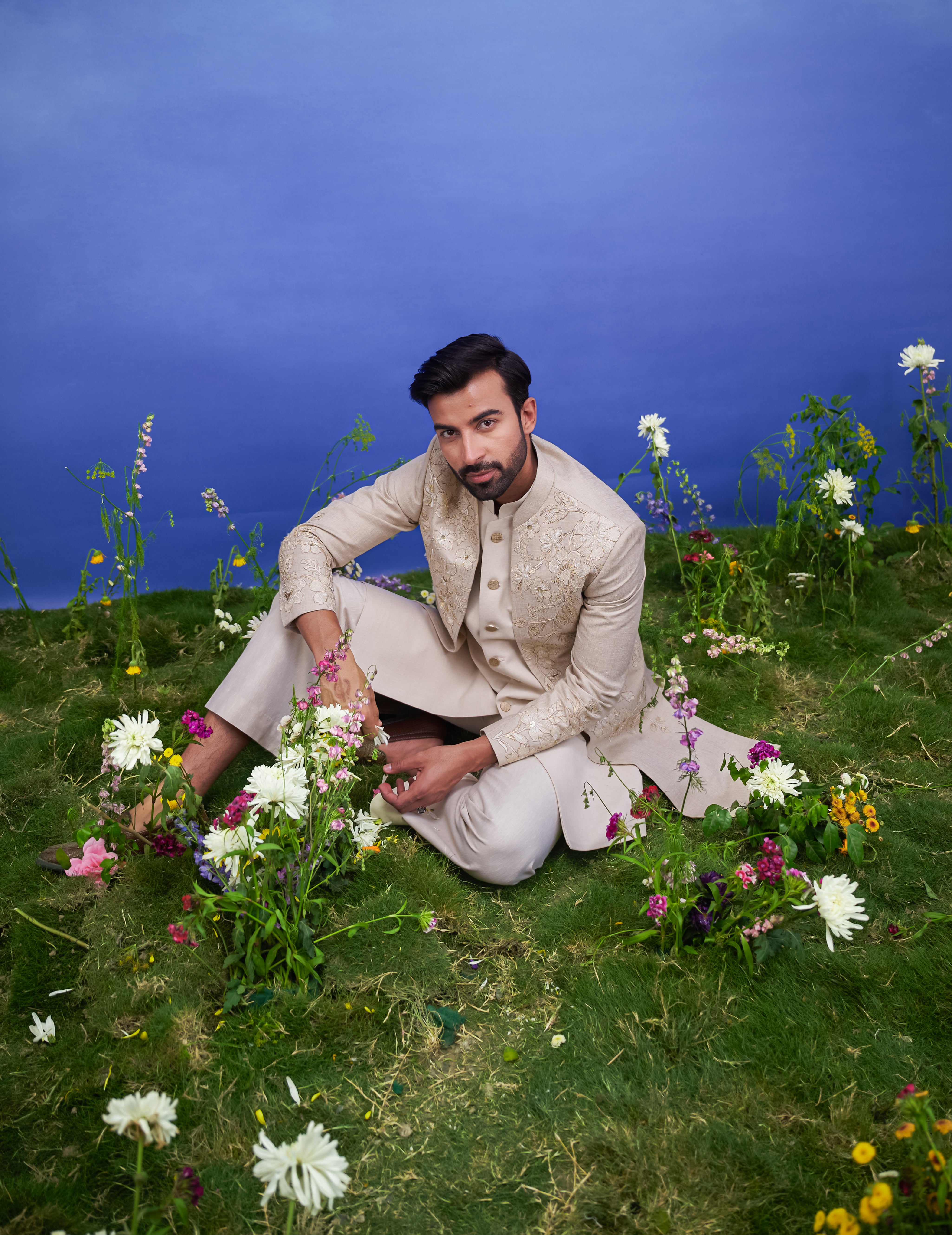 Men's cream Indo-western suit featuring a silk blend top, trousers, and long sleeveless jacket with zari work.