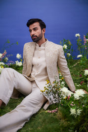 Cream floral embroidered Indo-western suit for men, blending traditional elements with modern styling, featuring zari work, suitable for weddings.