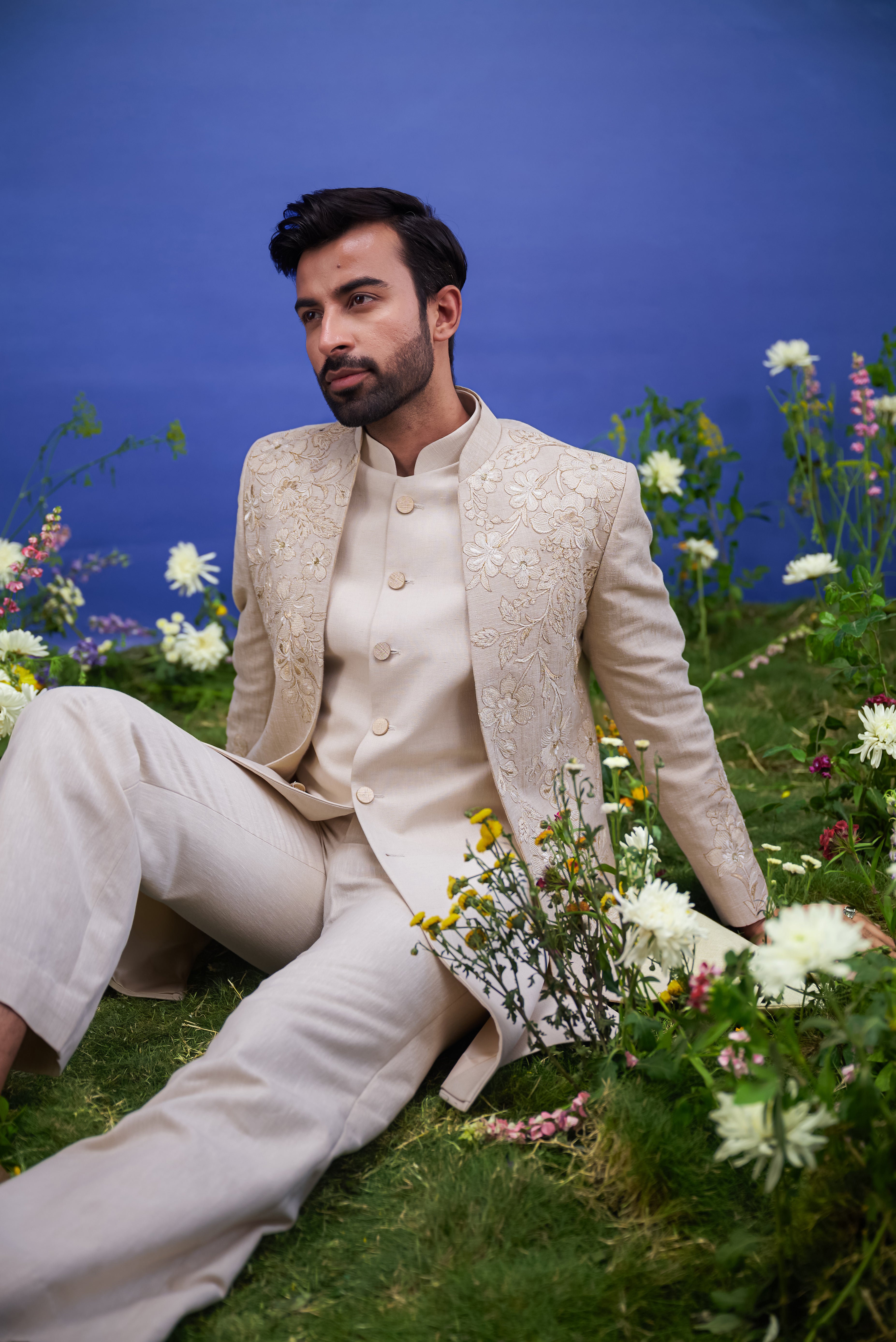 Cream floral embroidered Indo-western suit for men, blending traditional elements with modern styling, featuring zari work, suitable for weddings.