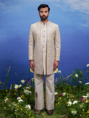 Cream Indo-western suit featuring a floral design and zari accents, designed for a distinguished male look.