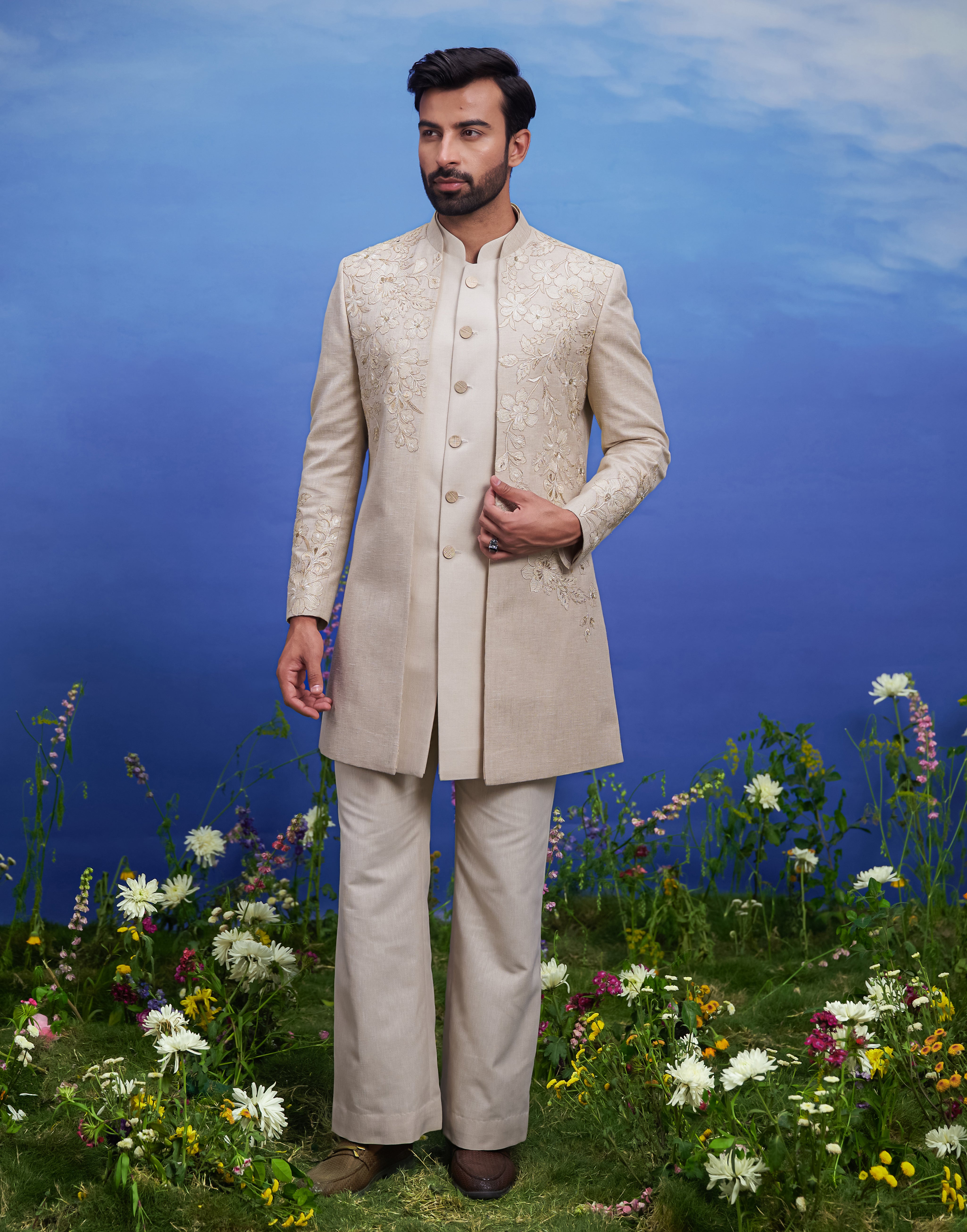 Cream floral embroidery open Indo-western outfit, men's ethnic fusion wear, featuring a silk blend top, trousers, and long sleeveless jacket with zari work.