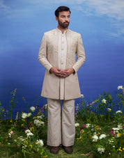 Elegant men's Indo-western outfit with cream floral embroidery and zari, suitable for cultural and celebratory events.
