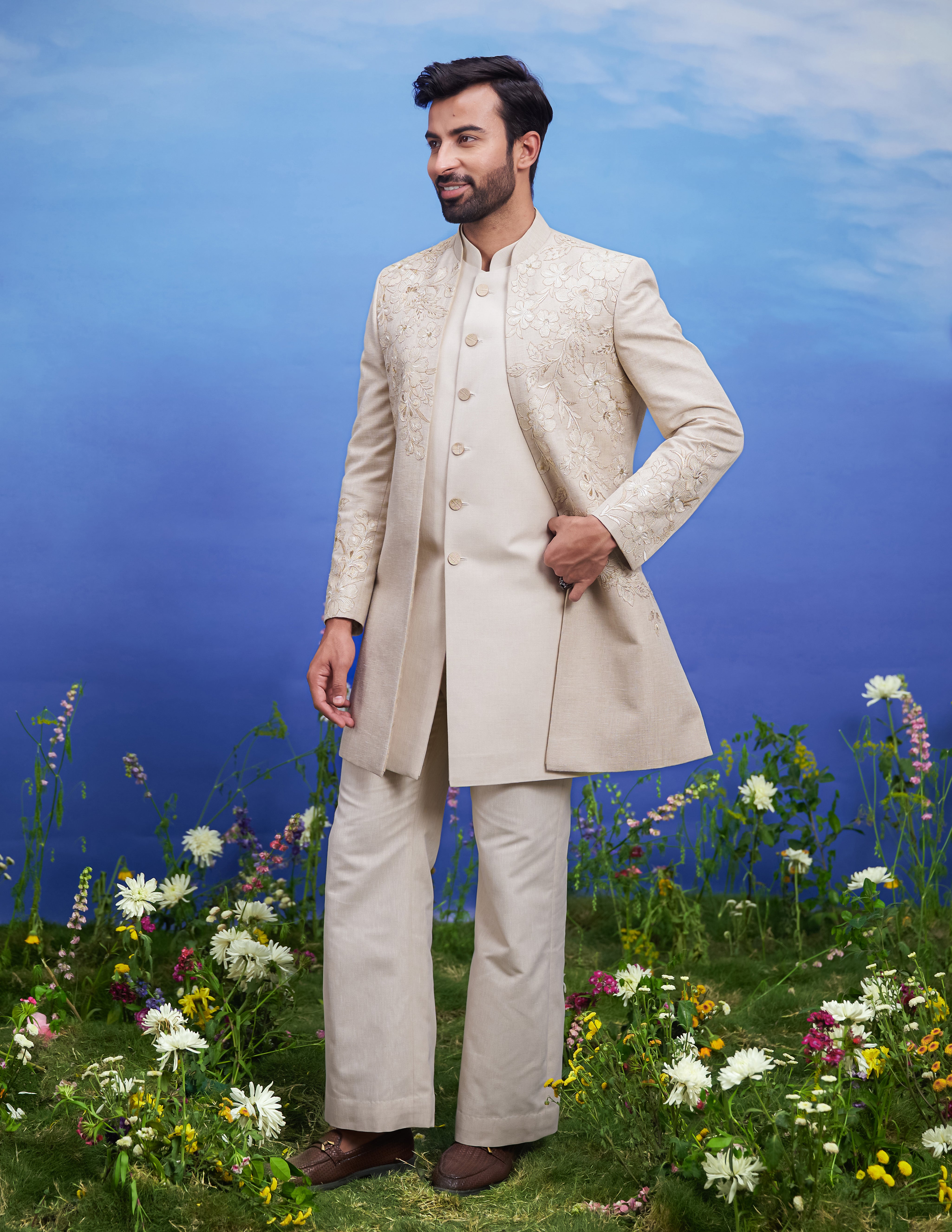 Cream Indo-western attire showcasing floral embroidery and zari highlights, tailored for a sophisticated men's style.