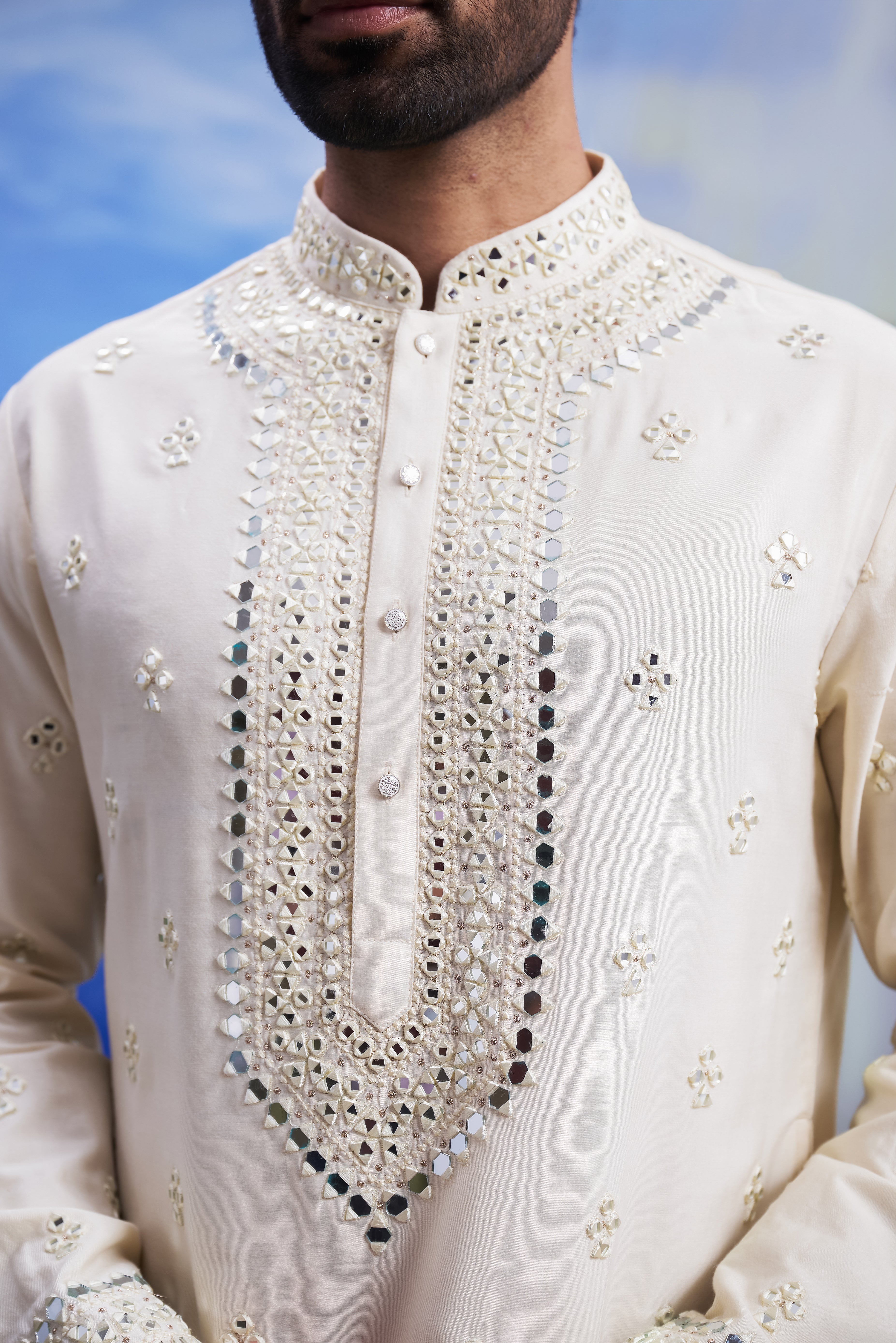 Men's cream kurta set with mirror work embroidery, displayed on a product page with size options.