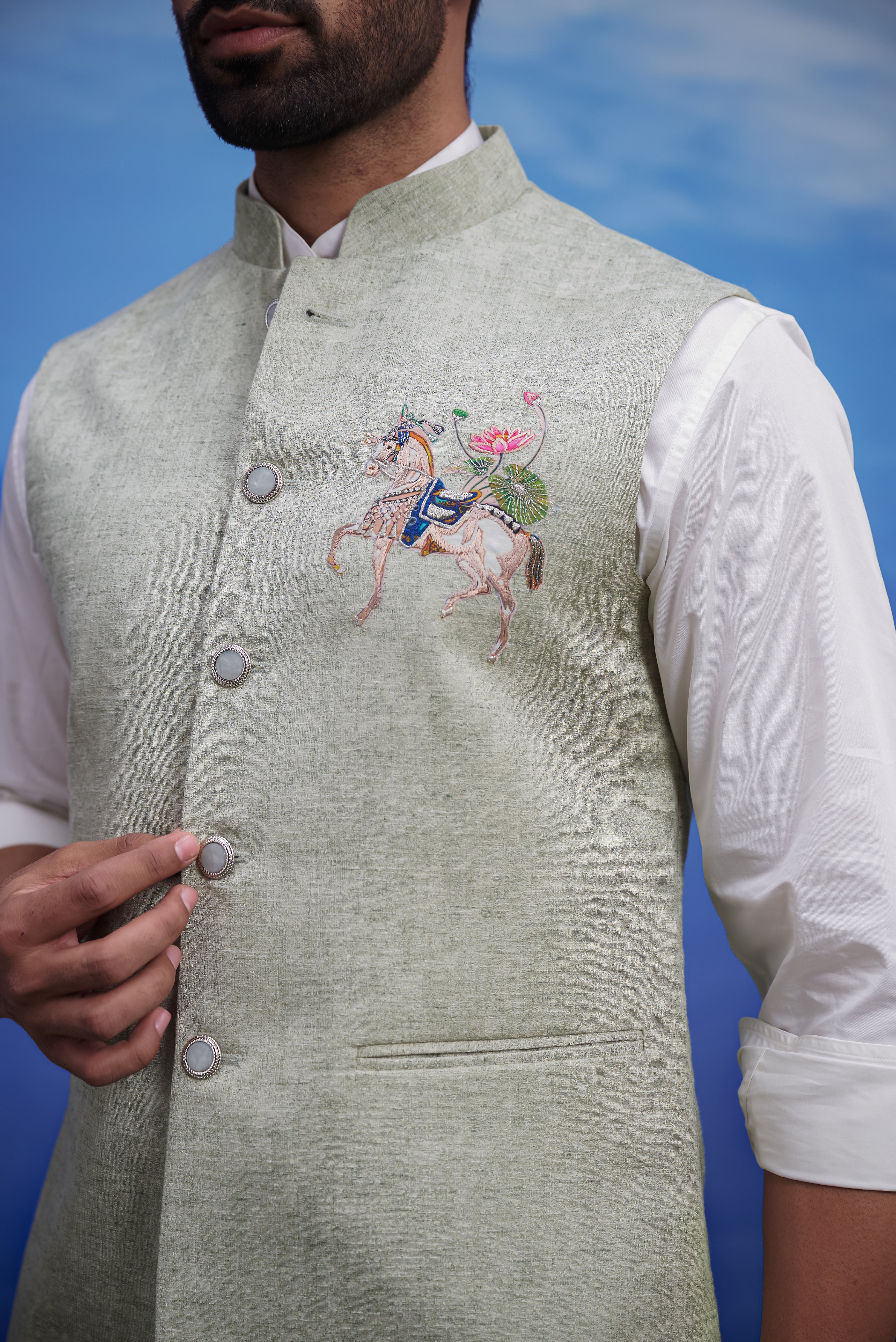 Close-up of the green Nehru jacket, highlighting the embroidered motif and linen blend fabric.