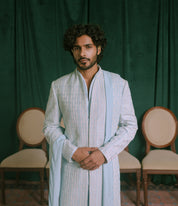 A man wearing a embroidered light blue vertically striped traditional long sherwani/ indowestern along with a embroidered stole