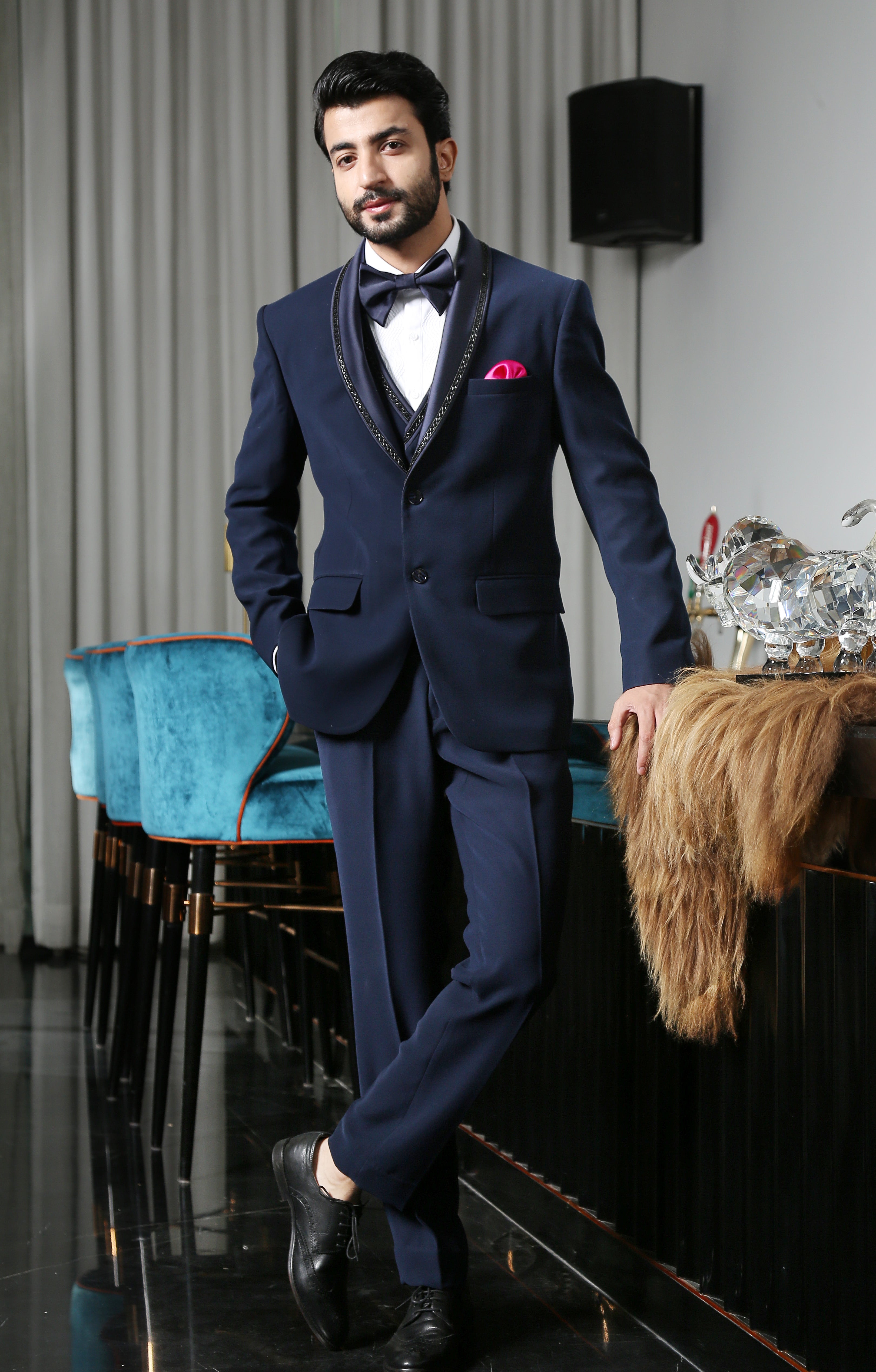 A luxurious navy blue designer suit with intricate embroidery, a timeless classic.

