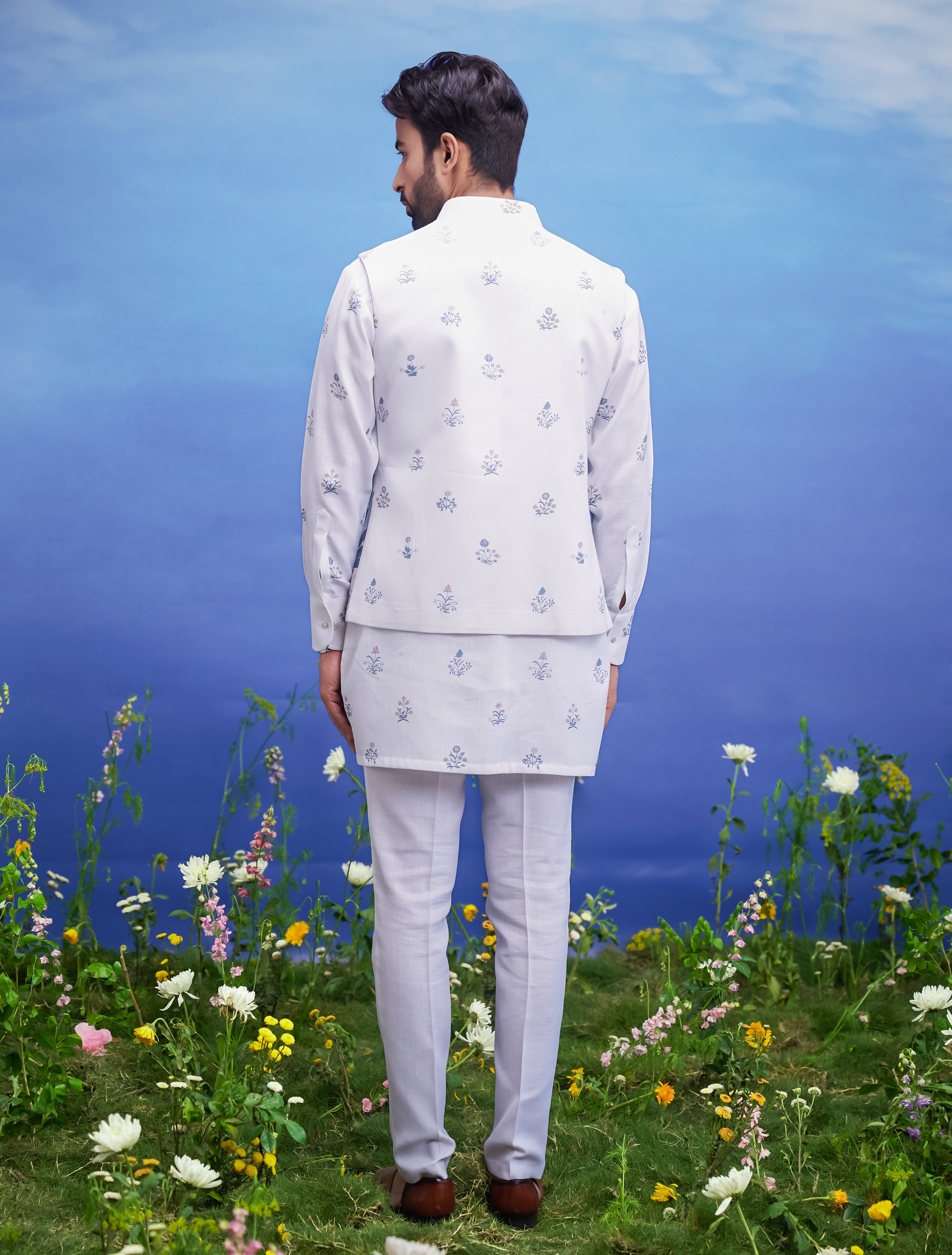 A white kurta jacket set with a floral print, featuring a kurta, jacket, and pajama, ideal for men's ethnic wear.