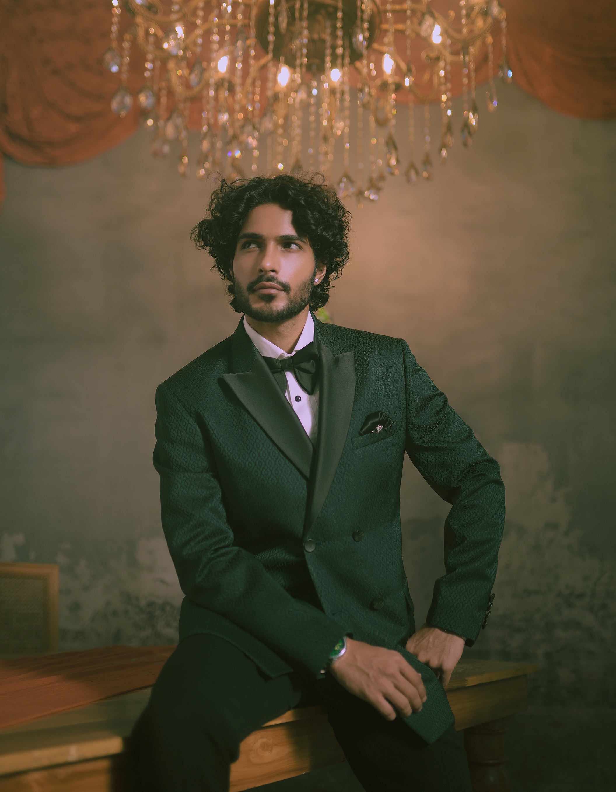 A man in a dark green double-breasted tuxedo with satin lapels, a white shirt, and a bow tie.