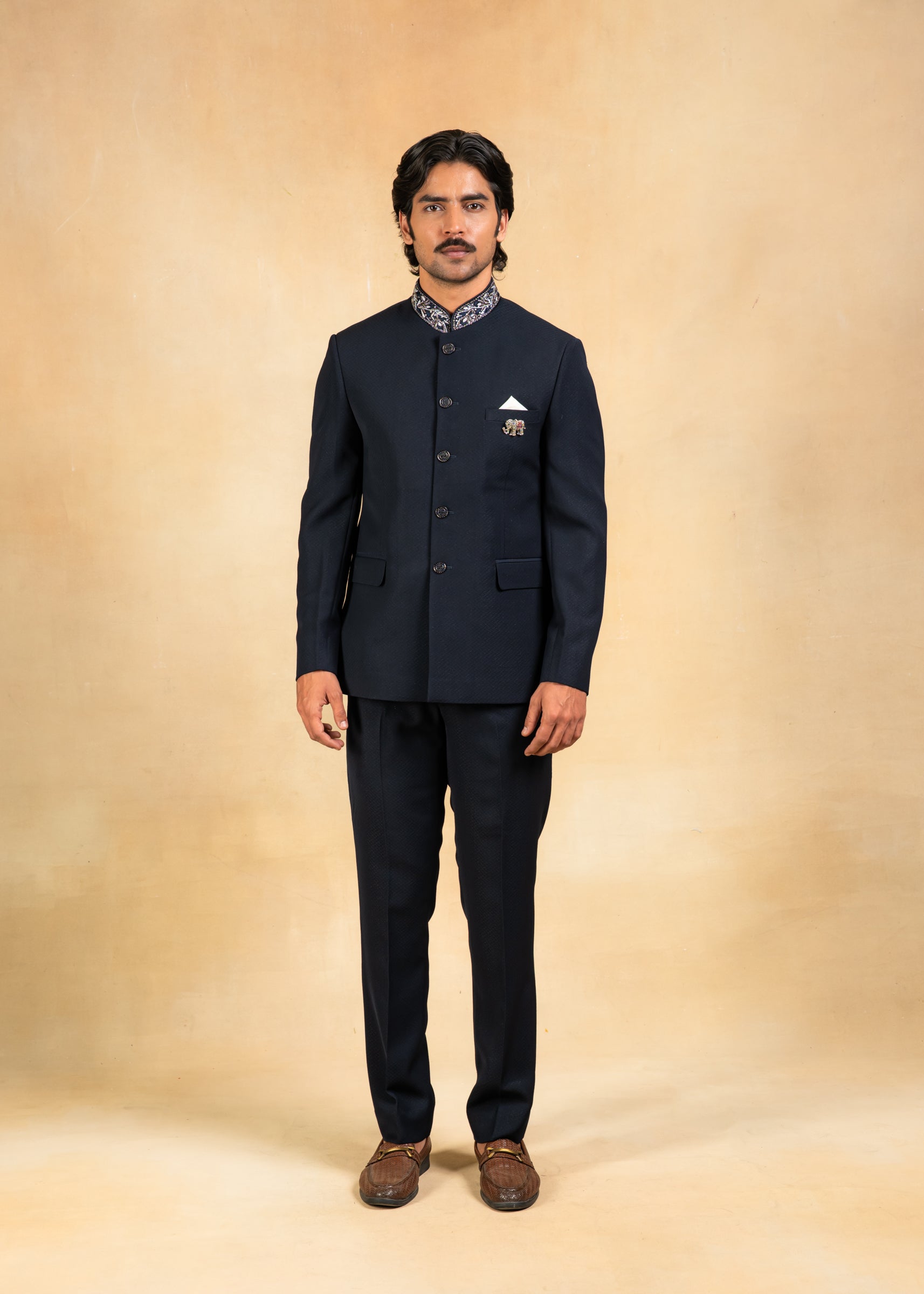 Man wearing a navy blue jodhpuri suit on a beige background