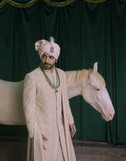 A man wearing a pink-colored embroidered sherwani.