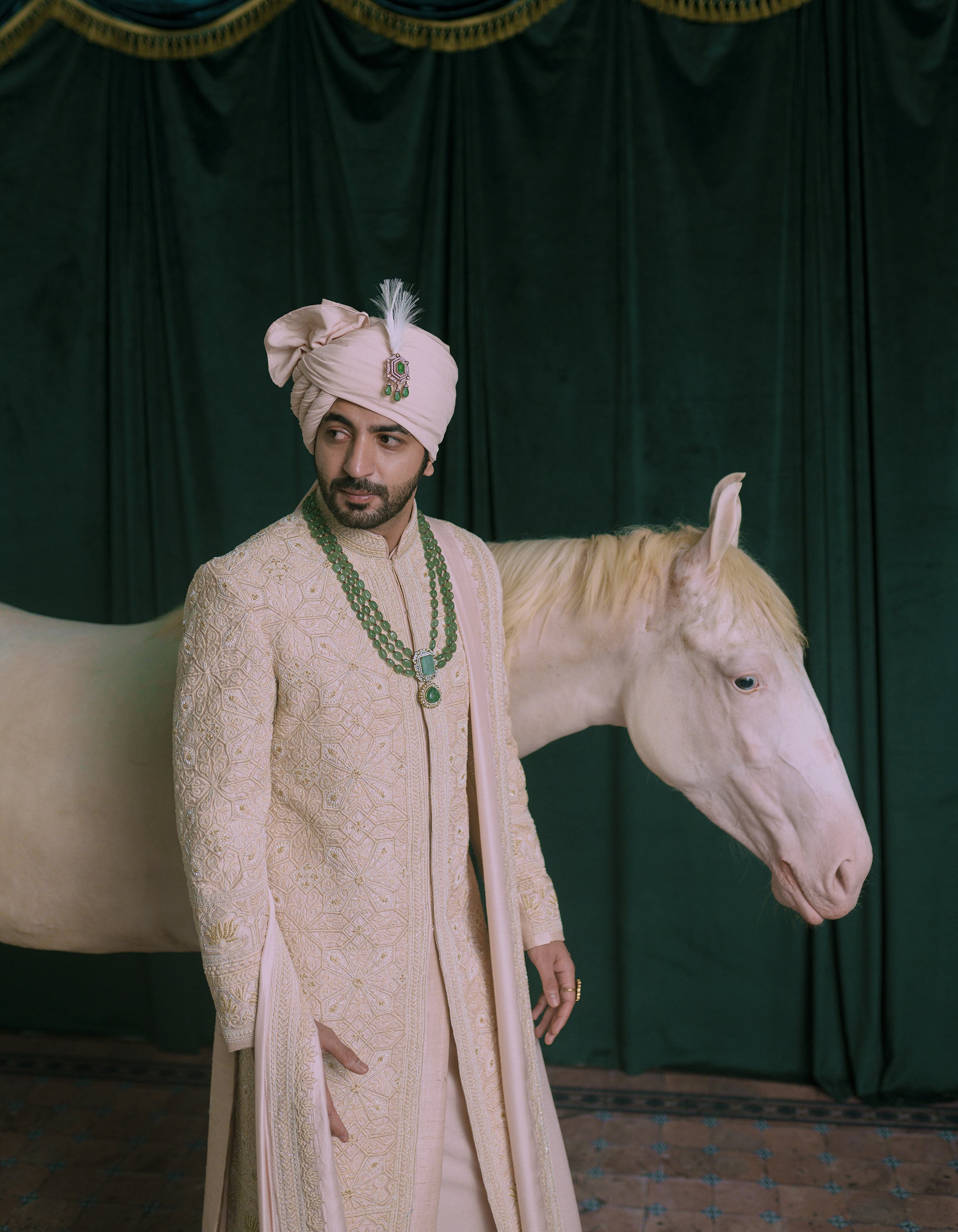 A man wearing a pink-colored embroidered sherwani.